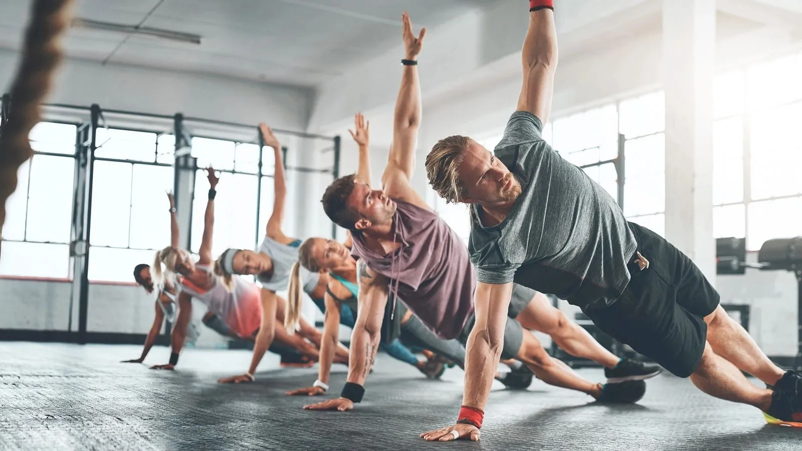 Group fitness class doing side planks in a bright studio