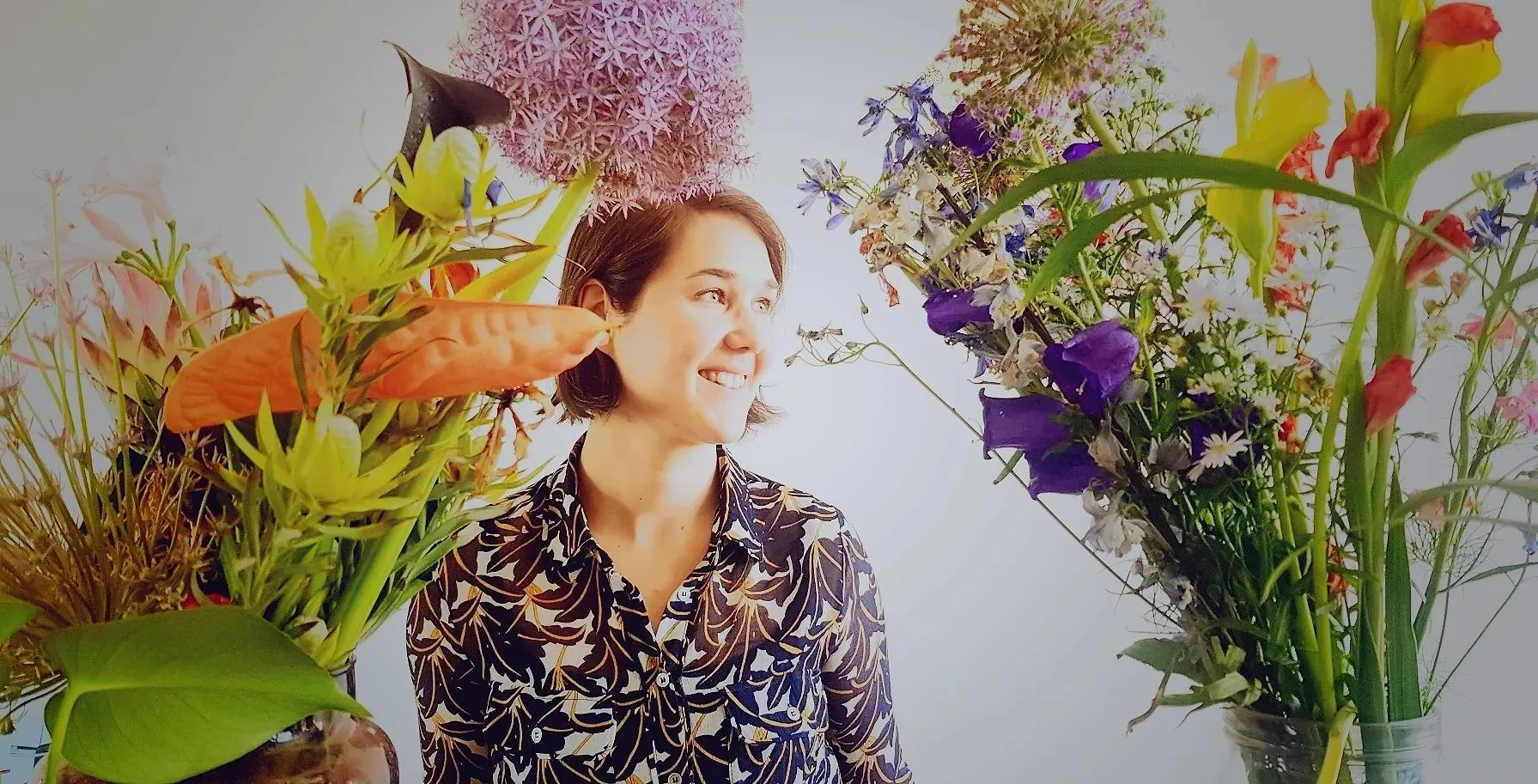Kathryn Rutherford smiling, surrounded by large bouquets of flowers