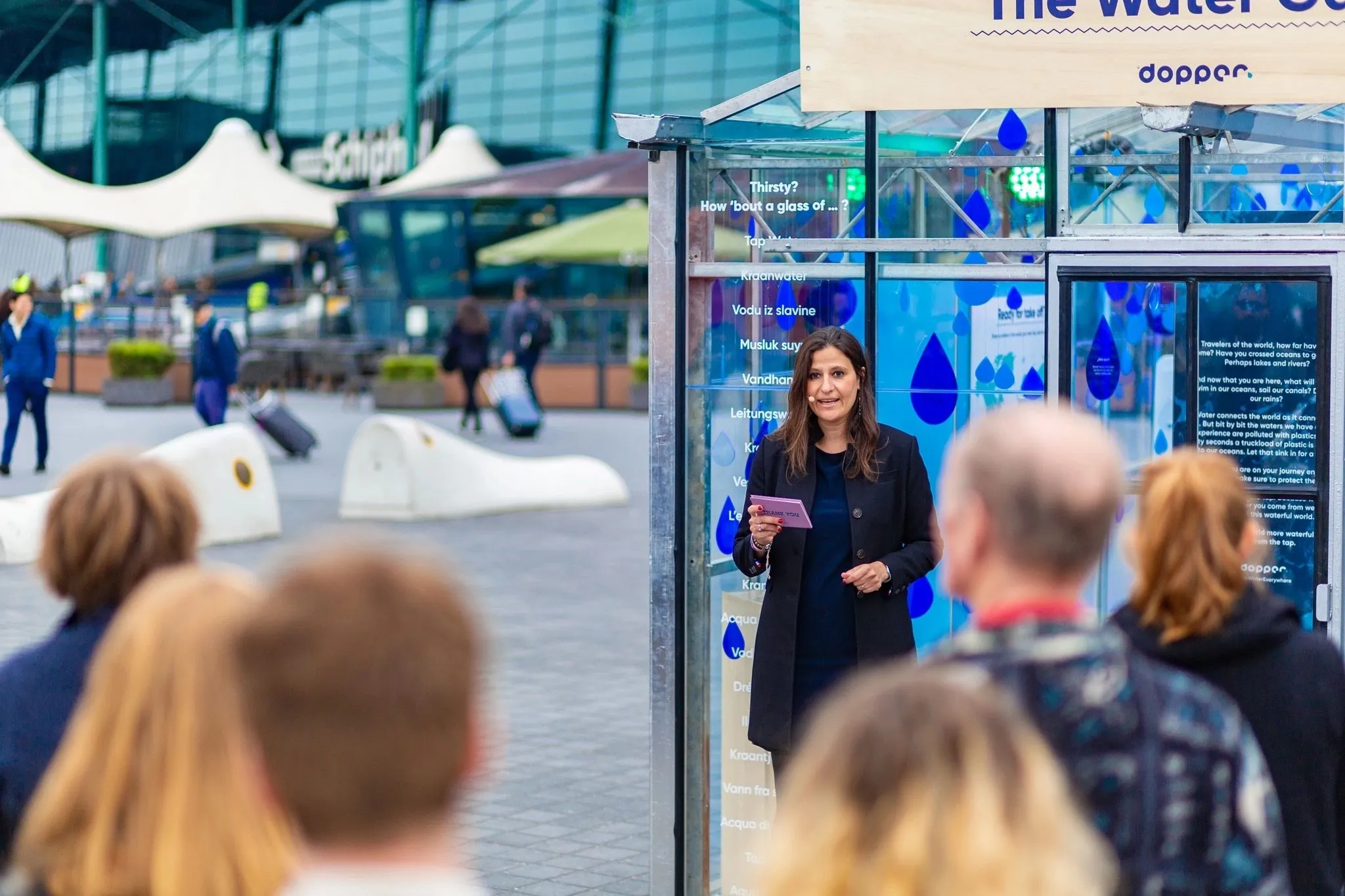 Woman presenting to an audience outside a Dopper water pavilion