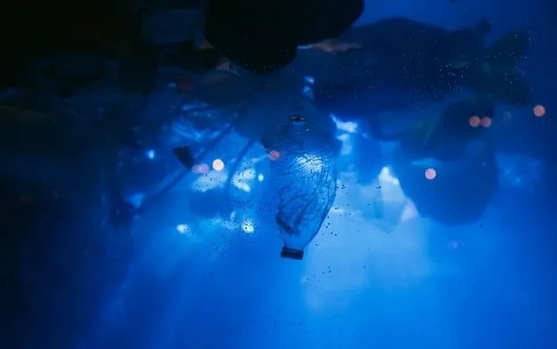 Plastic bottle floating underwater in blue light