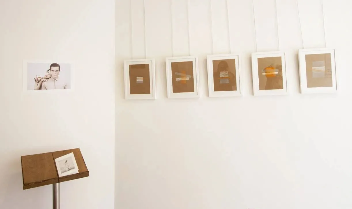 Small framed works hung in a row on a white gallery wall