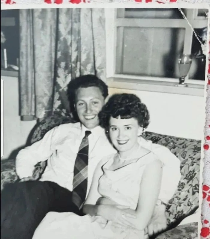 Black-and-white photo of a young couple smiling on a sofa